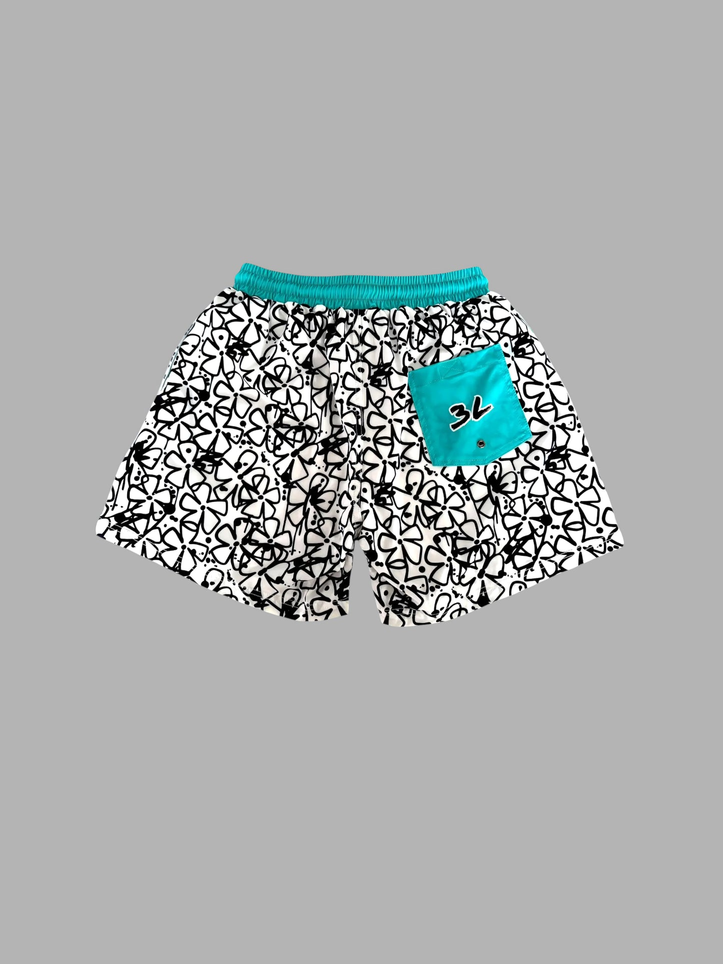 Black and white patterned shorts with a bright turquoise waistband and a matching turquoise pocket featuring a black graphic logo, shown on a solid gray background.